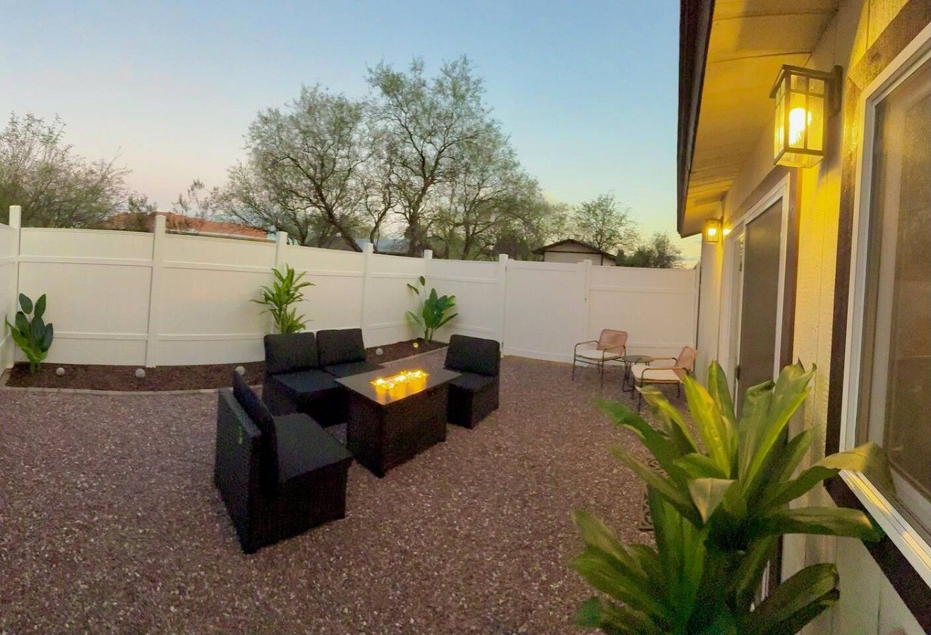 An outdoor patio with a fire pit, seating, and potted plants.