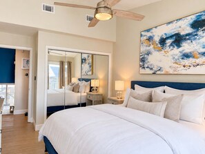 A hotel room with a large bed, a ceiling fan, a painting, and a view of the outside. - New- Ocean Mile Retreat | Pet Friendly | 2 Pools (Saint George Island)