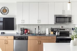 A modern kitchen with white cabinets, a microwave, a dishwasher, and a coffee maker. - City Views 2BR | Floor-to-Ceiling Windows A90 (Birmingham)