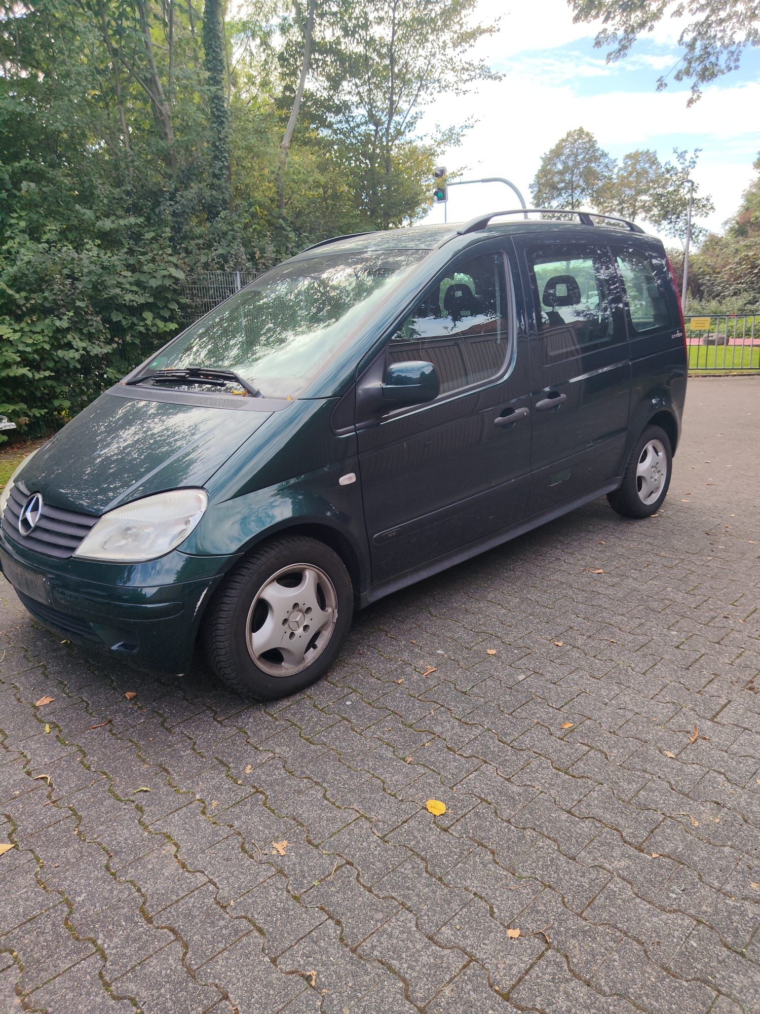Ein Kleinwagen auf befestigter Fahrbahn, im Hintergrund Bäume.