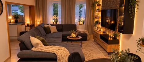 A modern living room with a sectional sofa, a coffee table, and a TV mounted on the wall.