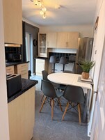 Una cocina compacta con electrodomésticos modernos, una mesa de comedor con sillas y una pequeña planta en maceta.