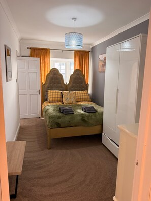 Ein Schlafzimmer mit Bett, Schrank, Spiegel und einer Tür.