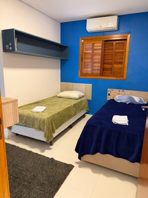 A bedroom with two beds, a window with wooden shutters, an air conditioning unit, and a small cabinet. - New Listing (Batatuba)