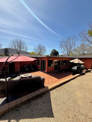 A patio area with outdoor seating, a barbecue grill, and a covered umbrella.