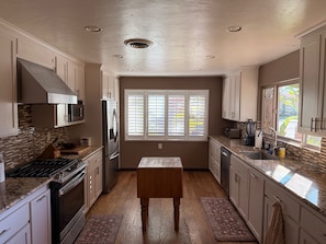 A kitchen with a central island, built-in appliances, and a window with blinds. - Modern Kitchen 3BR Home w/ Yard (San Luis Obispo)