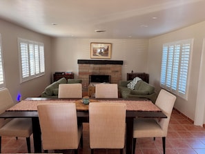 A dining area with a rectangular table, four chairs, a fireplace, and a framed picture above the mantel. - Modern Kitchen 3BR Home w/ Yard (San Luis Obispo)
