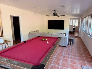 A pool table with balls, a sofa, a television, and a ceiling fan in a room with tiled flooring. - Modern Kitchen 3BR Home w/ Yard (San Luis Obispo)