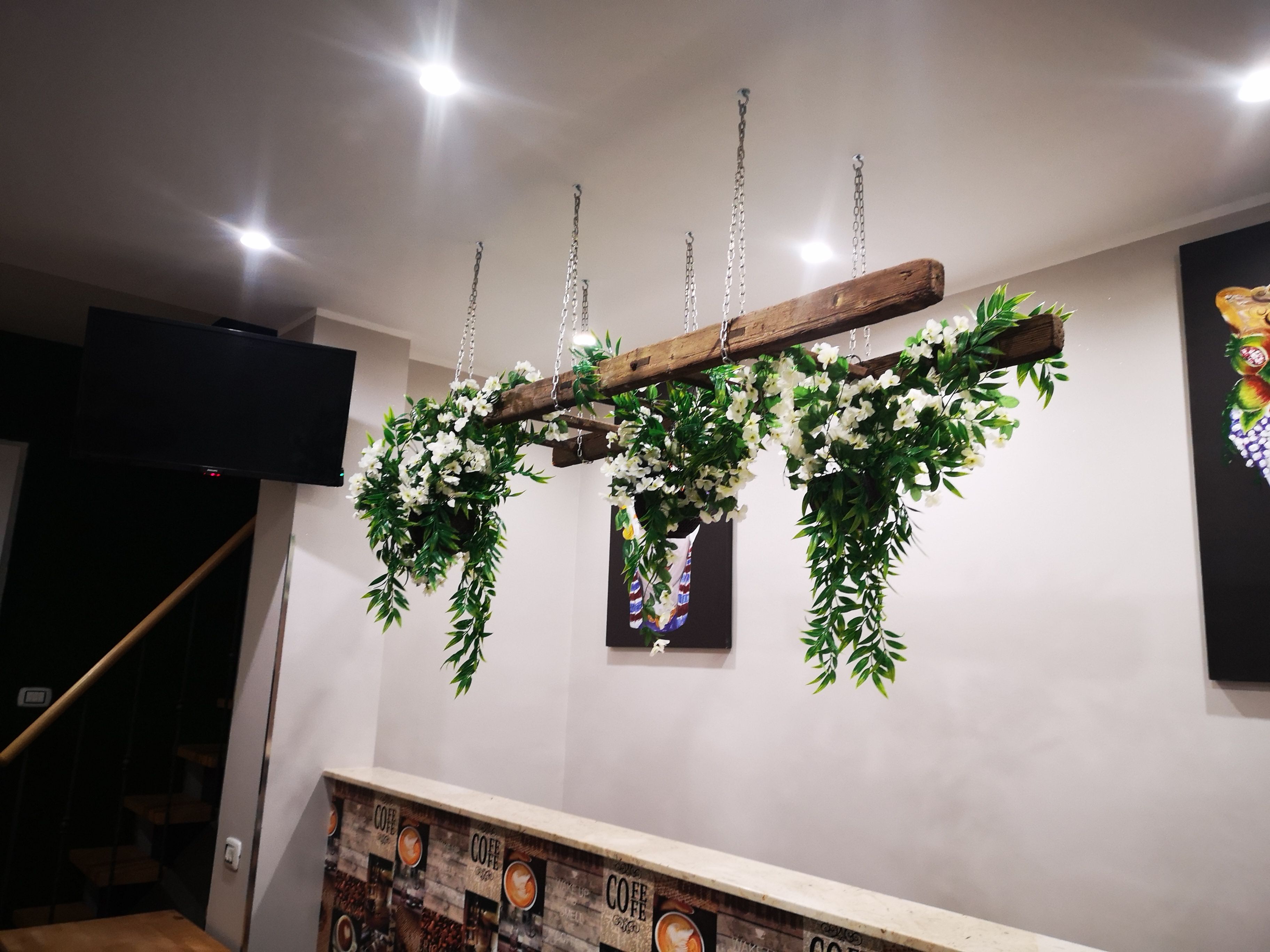 A wooden ceiling structure with hanging greenery and a coffee-themed wall.