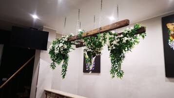 A wooden ceiling structure with hanging greenery and a coffee-themed wall.