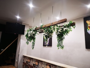 A wooden ceiling structure with hanging greenery and a coffee-themed wall. - New Listing (Tonnarella)