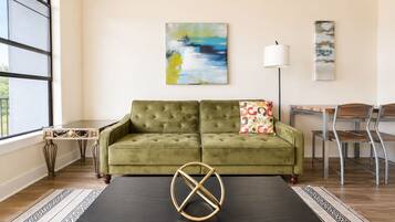 A living room with a green sofa, a coffee table, and a painting on the wall.