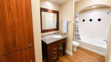 A bathroom with a wooden vanity, a sink, a toilet, and a bathtub.