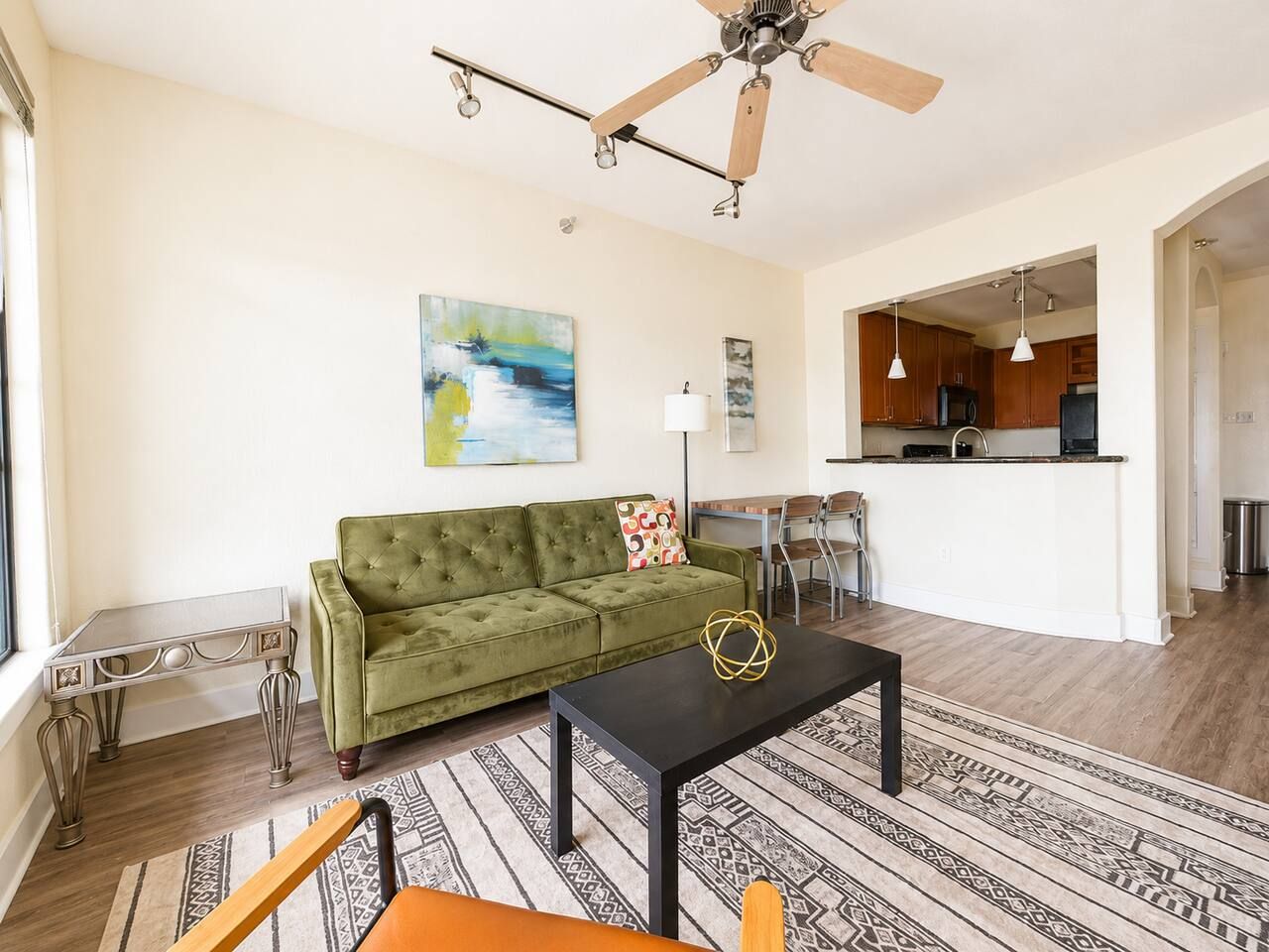 Ein Wohnzimmer mit einem grünen Sofa, einem schwarzen Couchtisch und einem gemusterten Teppich.