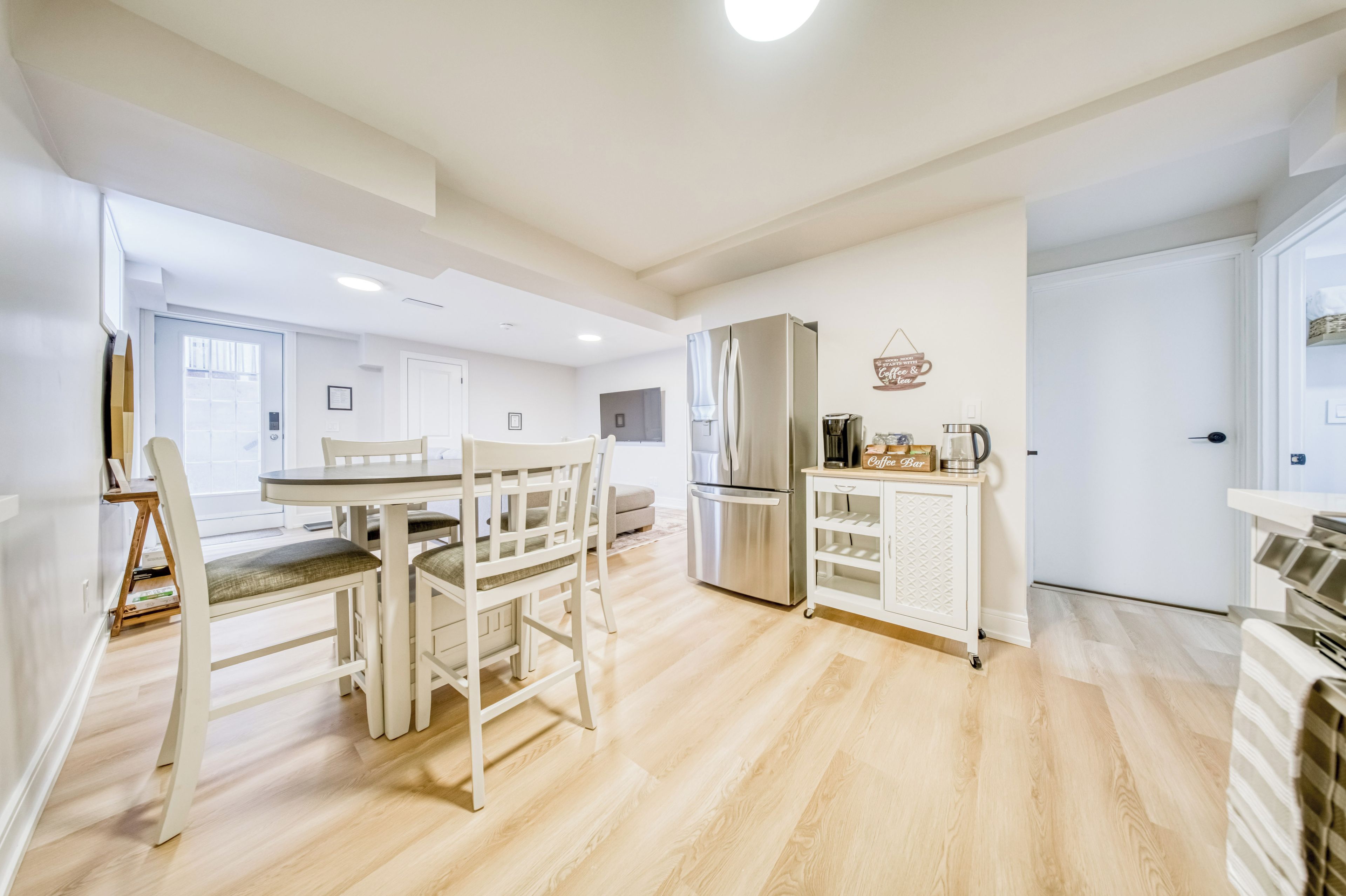 A modern kitchen with a dining area, stainless steel appliances, and a coffee station.