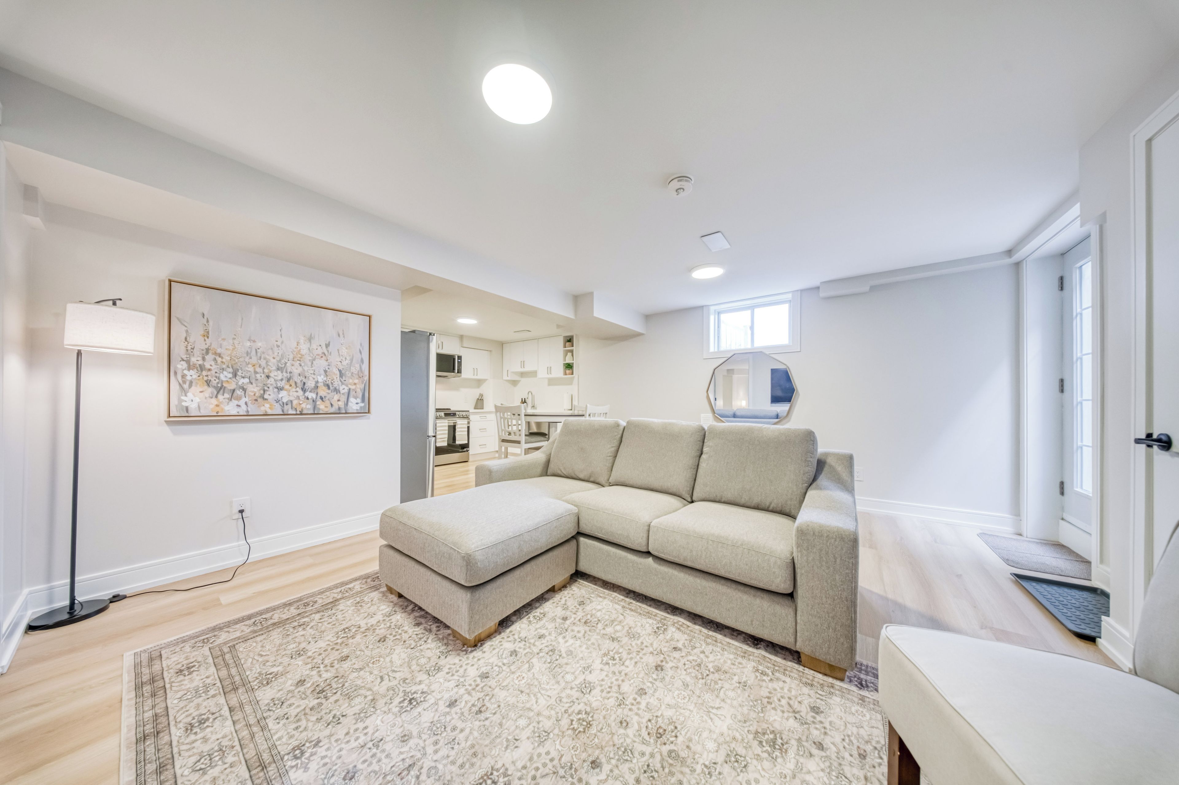 A modern living room with a sectional sofa, a flat-screen TV, and a large painting on the wall.