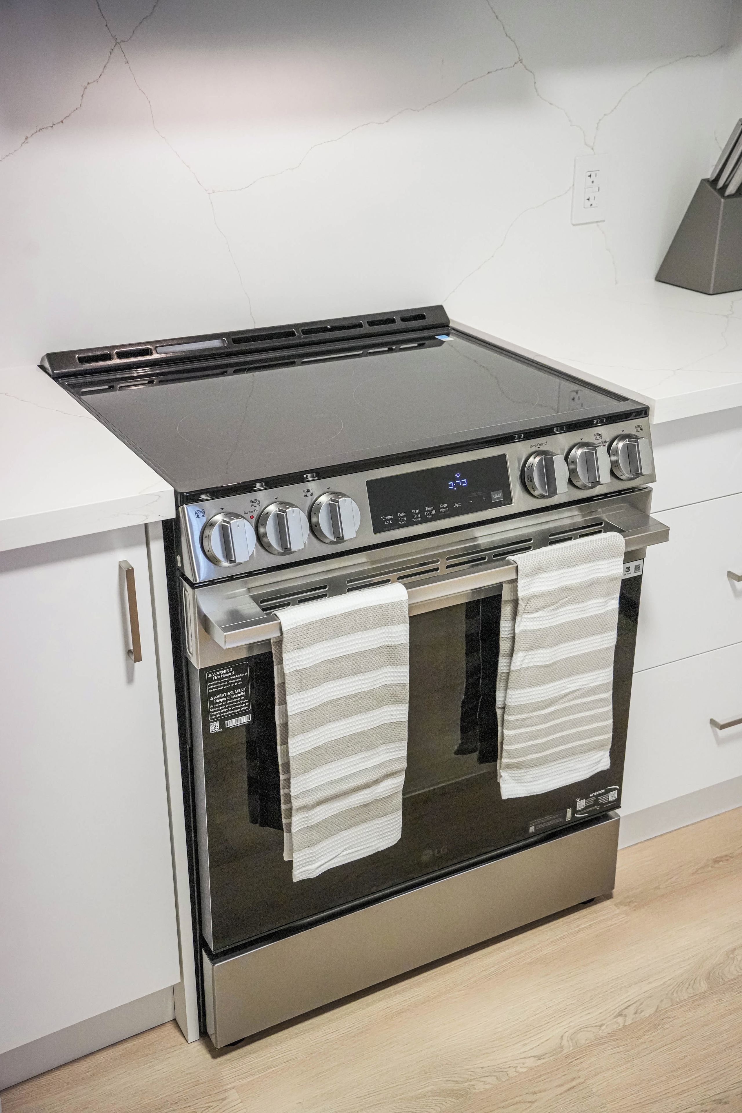 A stainless steel kitchen with a built-in oven and stovetop, featuring control knobs and a digital display.