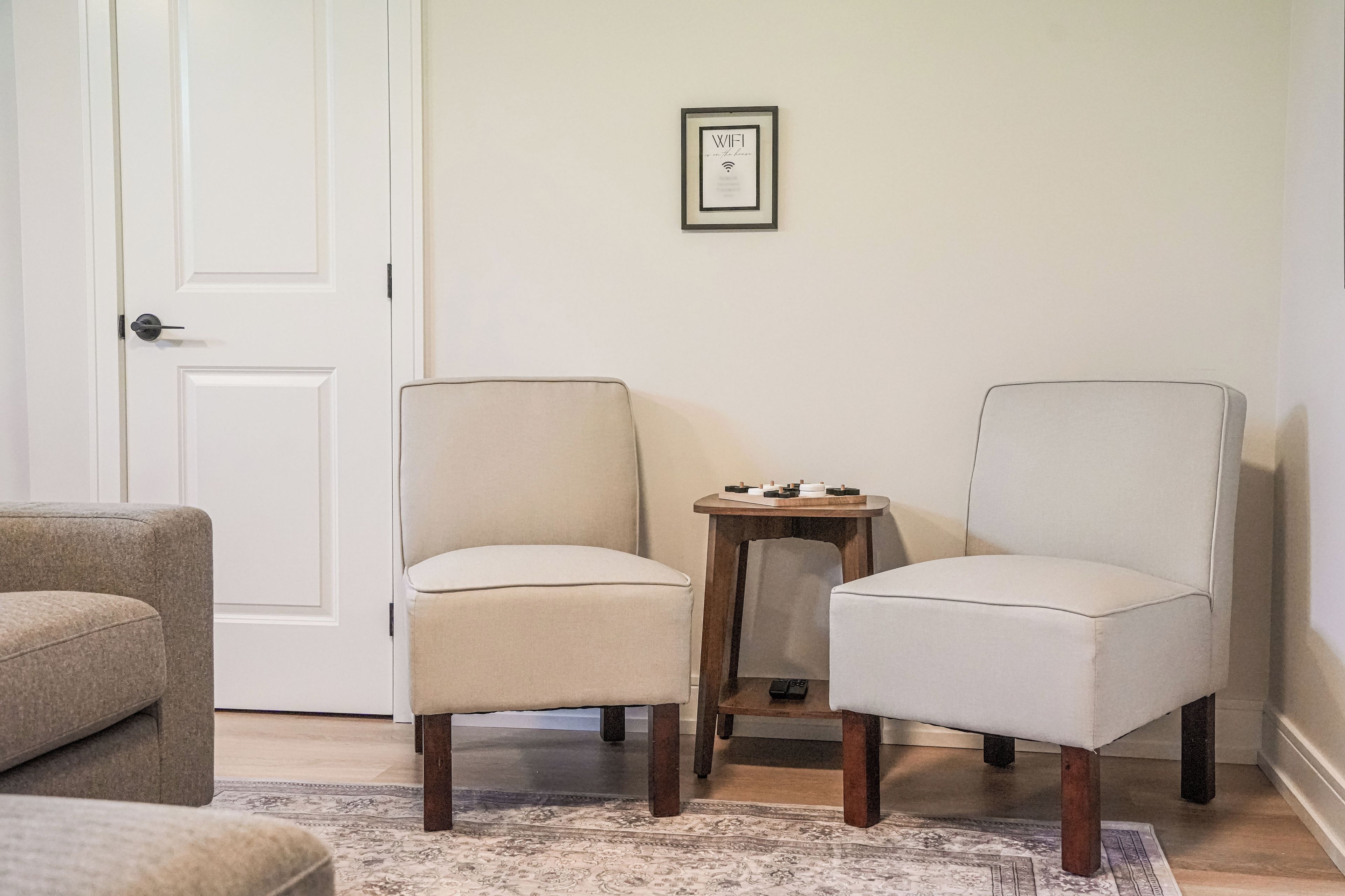 A room with two armchairs, a small wooden side table, and a door.