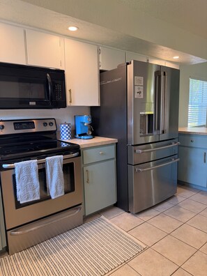 A kitchen with stainless steel appliances, including a microwave, stove, and refrigerator. - Welcome to the Sandy Beach Oasis, your relaxing New Smyrna Beach getaway! (New Smyrna Beach)