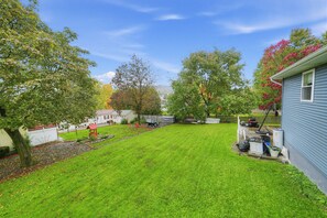 A well-maintained backyard with a lawn, trees, and a small shed. - Spacious 4BR Home Near Binghamton & UHS (Endicott)