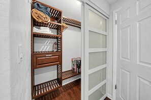 Walk-in closet with built-in wooden shelving behind a frosted glass sliding door. - Spacious 4BR Home Near Binghamton & UHS (Endicott)