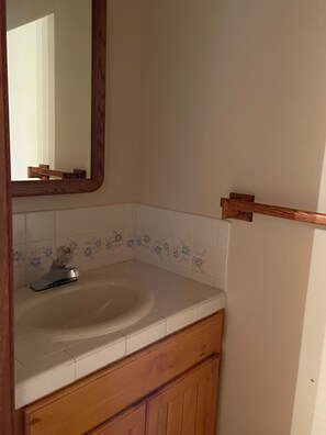 Une salle de bain avec un meuble-lavabo en bois, un lavabo blanc et un miroir.