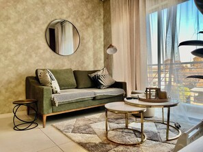 Ein Wohnzimmer mit einer Couch, einem runden Couchtisch, einer Stehlampe und Blick auf ein Gebäude durch ein Fenster.