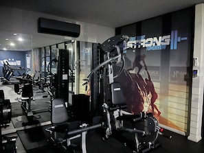 A gym with various exercise equipment, including a bench press and a squat rack. - Cozy Retreat in Carlswald 229 (Johannesburg)