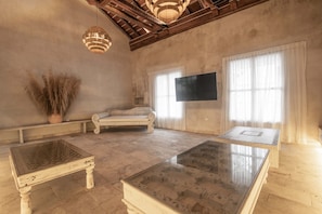 A spacious room with a large sofa, a glass-top coffee table, and a flat-screen TV mounted on the wall. - 11 Bedroom Luxury Villa in Old City (Cartagena de Indias)
