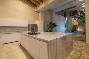 A modern kitchen with a central island, built-in appliances, and a view of a swimming pool. - 11 Bedroom Luxury Villa in Old City (Cartagena de Indias)