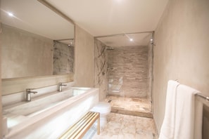 Uma casa de banho moderna com um espelho grande, duas bacias e uma cabine de duche com banco.