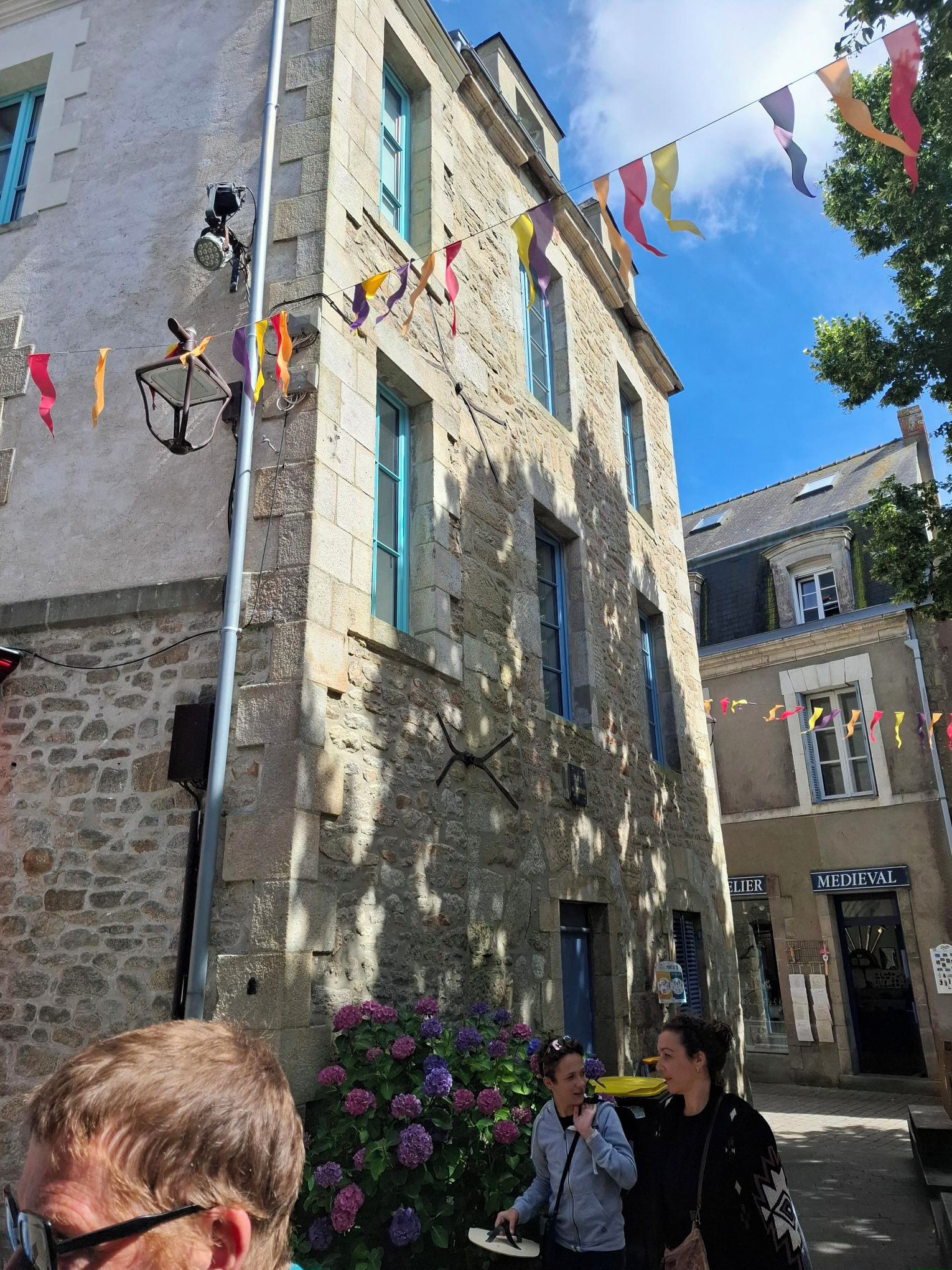 Ein Steinhaus mit einem Schild, auf dem 'MEDIEVAL' steht, und einem darunterliegenden Geschäft namens 'ELIER'.