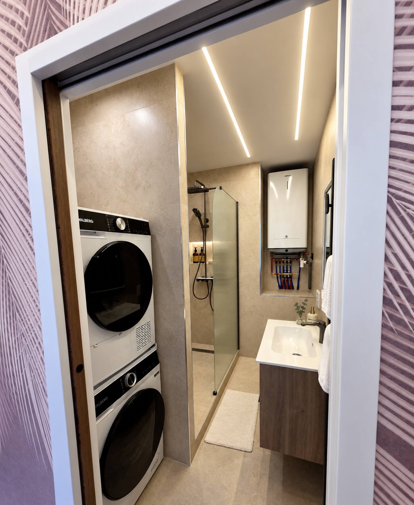 Une salle de bain moderne dotée d’un lave-linge intégré, d’une douche en verre et d’un meuble-lavabo avec miroir.