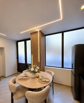Un espace repas moderne avec une table ronde, des chaises et un vase de fleurs.