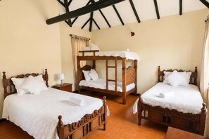 A room with three wooden beds, each with white bedding, and a wooden headboard. - Hotel Altair (Villa de Leyva)