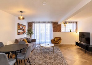A modern living room with a sofa, coffee table, and TV stand. - Luxury City Centre Apartment with Canal View (West Midlands)