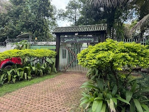 A gated entrance with a sign reading 'Saint Germany,' surrounded by lush greenery and a paved pathway.