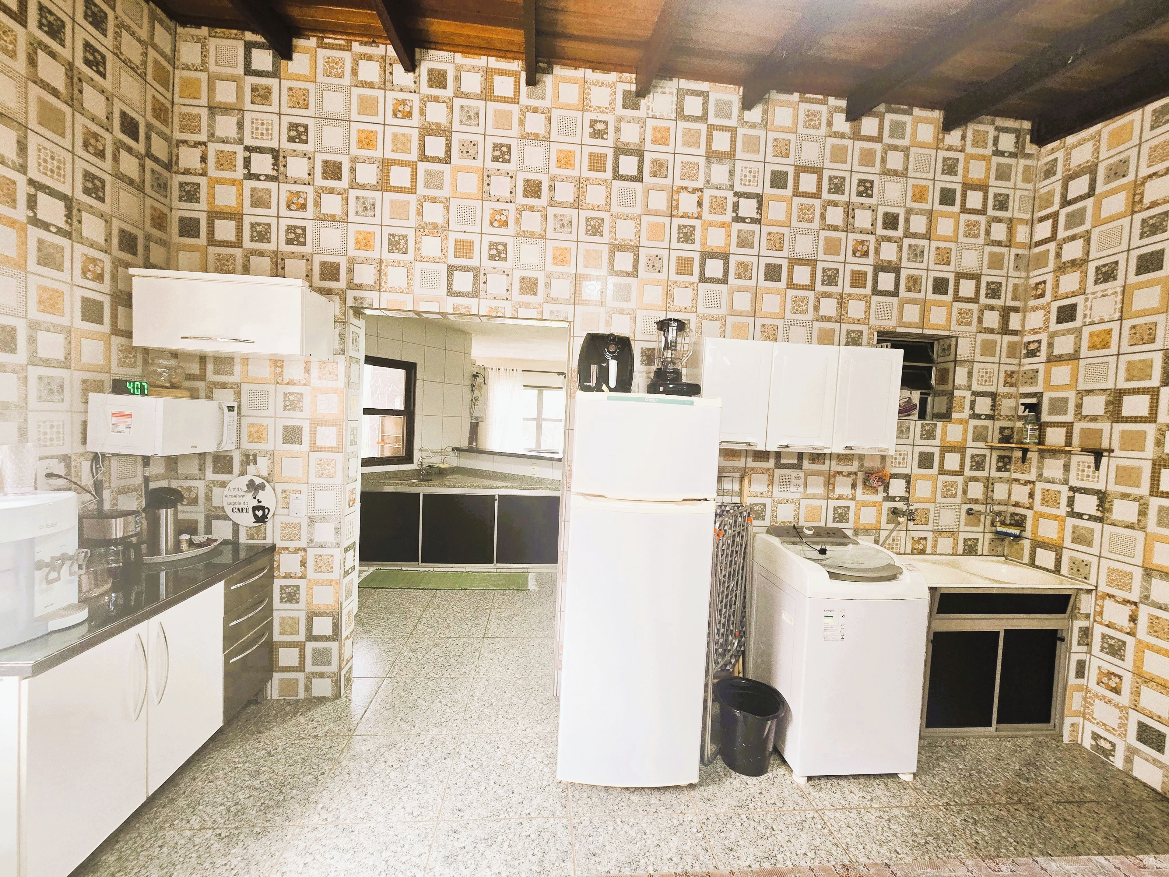 A kitchen with patterned tile walls, white cabinets, and a refrigerator.