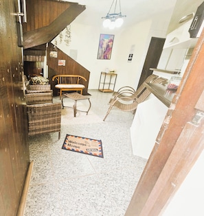 A cozy interior with wicker furniture, a wooden staircase, and a welcome mat.