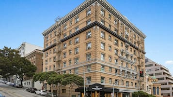 A multi-story building with a classic architectural style, featuring a prominent corner entrance and a visible storefront.