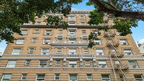 Um edifício de vários andares com fachada de tijolos, várias janelas e escadas de incêndio.