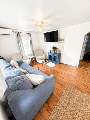 A living room with a sofa, armchairs, a coffee table, a TV, and a blue cabinet. - Lake Escape Cottage | Minutes to Paw Paw Lake + Wineries (Watervliet)