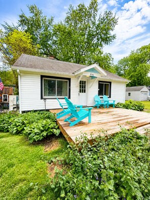 A small white house with a deck, two windows, and a door. - Lake Escape Cottage | Minutes to Paw Paw Lake + Wineries (Watervliet)