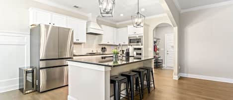 A modern kitchen with a central island, stainless steel appliances, and a bar stool seating arrangement.