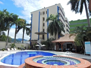 Un hotel con piscina, palmeras y un edificio con detalles azules.