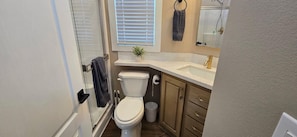 A compact bathroom with a toilet, sink, and shower. - A15 Cozy 1-bedroom mobile home with AC in welcoming Casa Grande (Casa Grande)