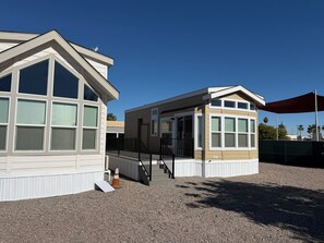 A two-story building with a covered porch and a staircase leading to the entrance. - A15 Cozy 1-bedroom mobile home with AC in welcoming Casa Grande (Casa Grande)