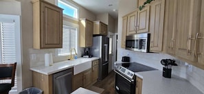 A kitchen with wooden cabinets, stainless steel appliances, and a dishwasher. - A15 Cozy 1-bedroom mobile home with AC in welcoming Casa Grande (Casa Grande)