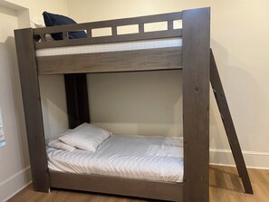 Un lit superposé avec une structure en bois et du linge de lit blanc.