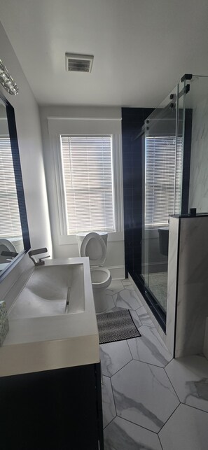 Un baño moderno con una bañera grande, un inodoro y una zona de ducha.